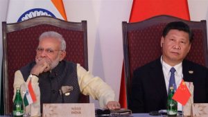 Indian Prime Minister Narendra Modi and Chinese President Xi Jinping sitting in a formal event with faces away from each other.